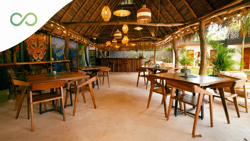 Open-air tropical restaurant featuring natural wood, lush greenery, woven lighting, and a thatched roof Green Certifications for Restaurants green loop
