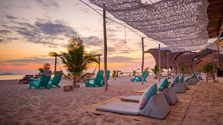 Sustainable beach club with palm trees, lounge chairs, and shaded seating at sunset EarthCheck Certification for Sustainable Beach Clubs green loop