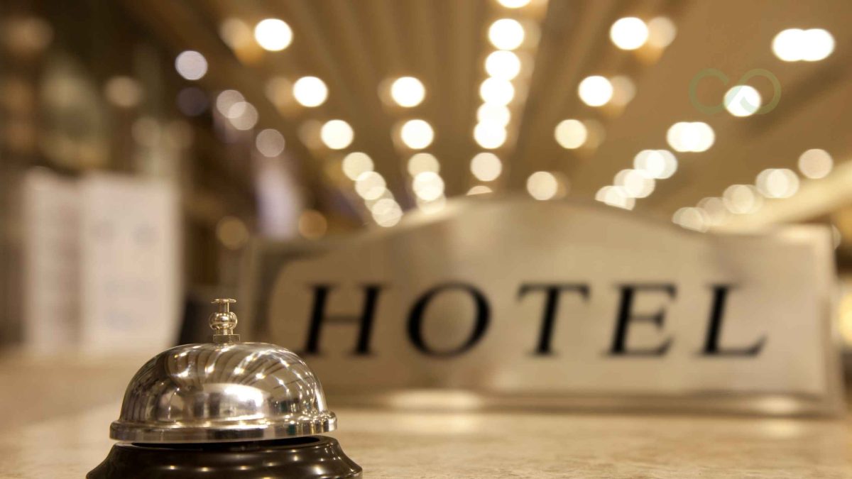 A polished silver hotel service bell on a reception counter, with a softly blurred hotel sign and warm ambient lighting in the background LEED Certification for Hotels: common mistakes to avoid green loop