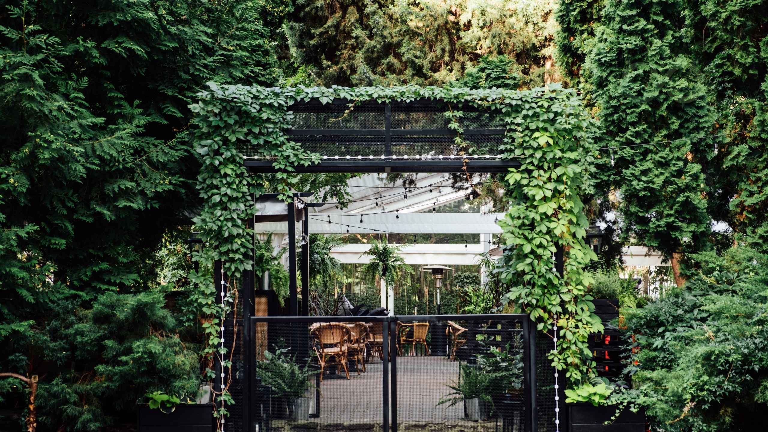 A modern outdoor dining area surrounded by lush greenery, featuring a contemporary pergola covered in climbing plants and a tranquil garden setting Biophilic Hotel Design: A 2026 Guide for US and Caribbean Resorts green loop