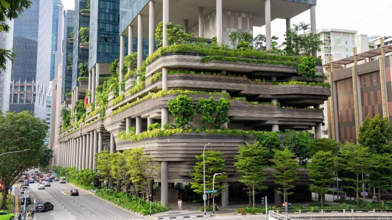 Contemporary urban architecture featuring a multi-level building with lush green terraces, landscaped balconies, and integrated trees, surrounded by modern skyscrapers and busy city streets Sustainable Procurement for Hotels: Green Supply Chain 2026 green loop